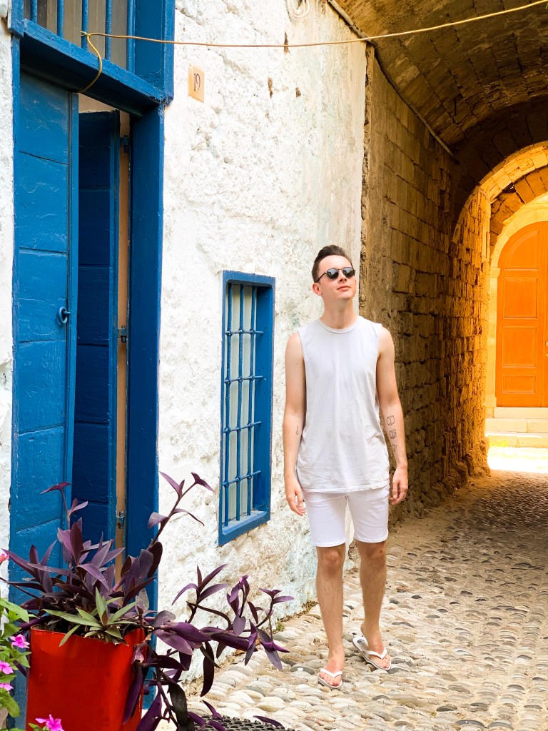 A man in a grey vest stands in a cobbled street in Medieval Old Town Rhodes